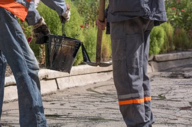 Yol onarım. İş ayrıntıları, işçi reçine yol yüzeyi asfalt karşılamak için dök.