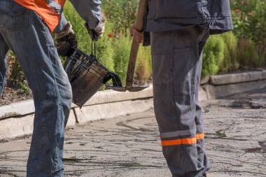 Yol onarım. İş ayrıntıları, işçi reçine yol yüzeyi asfalt karşılamak için dök.