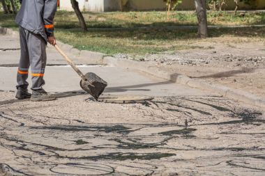 Yol onarım. İş ayrıntıları, işçi reçine yol yüzeyi asfalt karşılamak için dök.