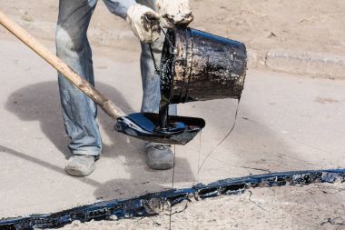 Yol onarım. İş ayrıntıları, işçi reçine yol yüzeyi asfalt karşılamak için dök.