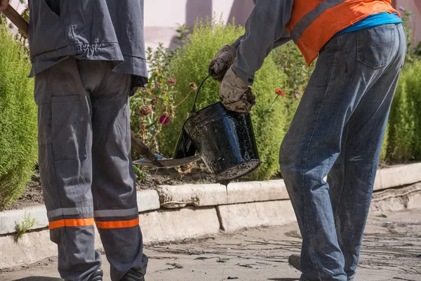 Yol onarım. İş ayrıntıları, işçi reçine yol yüzeyi asfalt karşılamak için dök.
