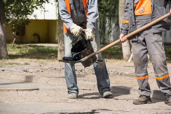 Yol onarım. İş ayrıntıları, işçi reçine yol yüzeyi asfalt karşılamak için dök.