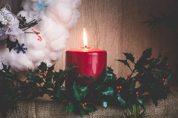 一个燃烧的蜡烛和冬青树枝的背景下的圣诞花环棉羊毛 — 图库照片