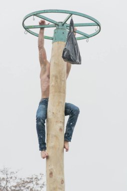 Tiraspol, Moldova - 18 Şubat 2018: ödül için ahşap bir direğe tırmanma genç adam. Slav halk pagan tatil Maslenitsa (Shrovetide) - bahar sembolik bir toplantı.