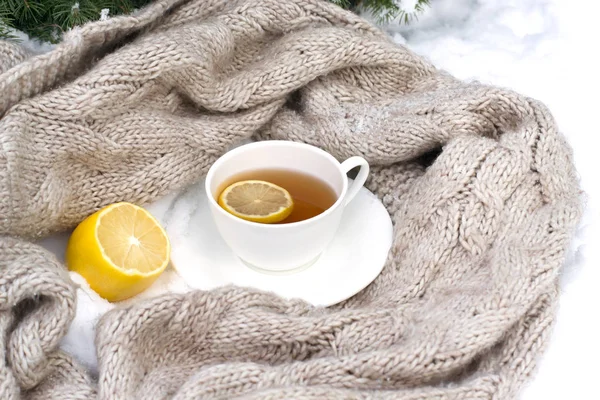 Tasse blanche de thé enveloppée dans une écharpe tricotée sur une soucoupe, citron i — Photo