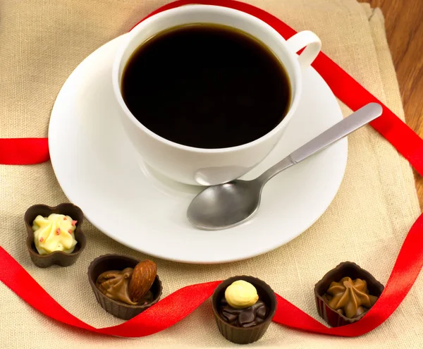 Xícara branca de café com chocolates e nozes de madeira em clos de serapilheira — Fotografia de Stock