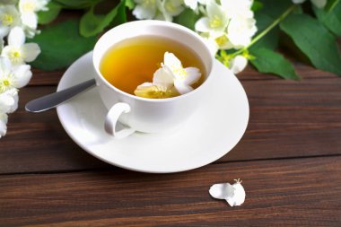 Yasemin ahşap bir masa üzerinde beyaz bir fincan çayla.