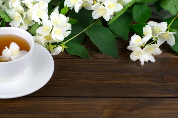 Τσάι με γιασεμί σε ένα λευκό φλιτζάνι σε ένα ξύλινο τραπέζι. — Φωτογραφία Αρχείου