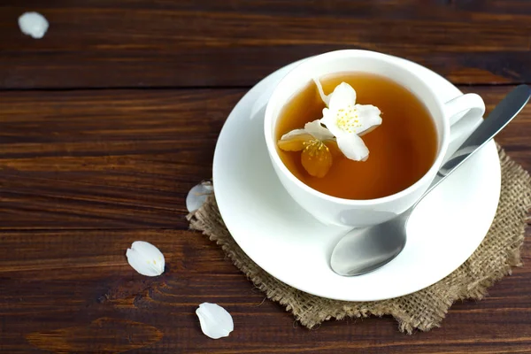 Tea with jasmine in a white mug on a wooden table — Stock Photo, Image