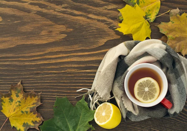ahşap bir masa üzerinde bir atkı sarılı bir limonlu sıcak çay