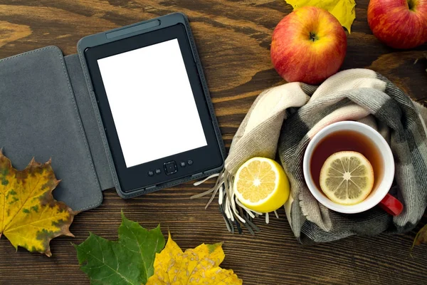 eBook ve ahşap bir masa üzerinde bir atkı sarılı bir limonlu sıcak çay