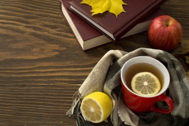 bir fincan çay limonlu sararmış yaprakları ve bir yığın kitap ile ahşap bir masa üzerinde bir atkı sarılı