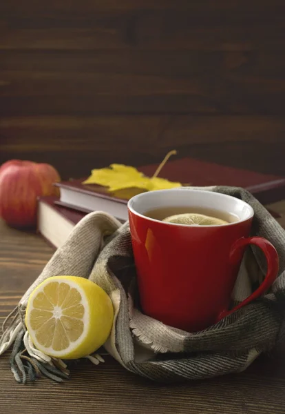 bir fincan çay limonlu sararmış yaprakları ve bir yığın kitap ile ahşap bir masa üzerinde bir atkı sarılı