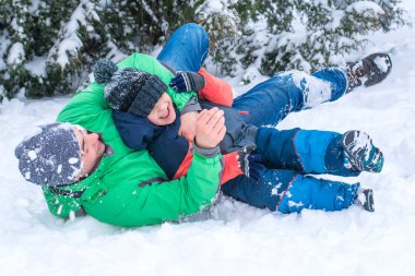 Baba ve oğul karda oynuyorlar.