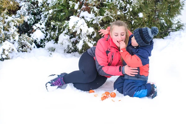 マンダリンと雪の腕抱擁で彼女の息子を持つ母 — ストック写真