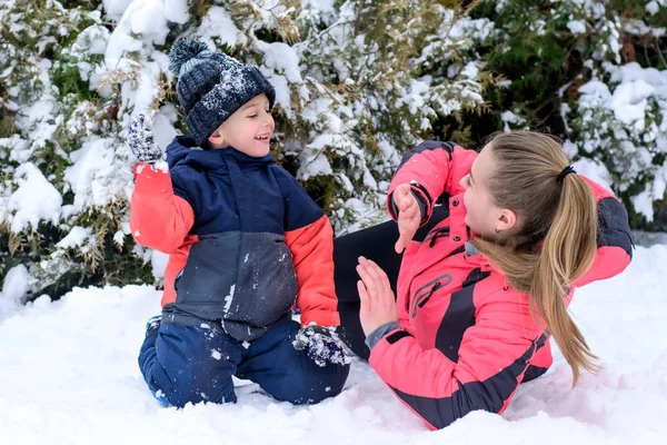 雪の上の腕抱擁で彼女の息子を持つ母 — ストック写真