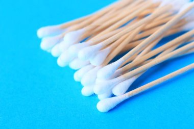 Beyaz pamuk uçlu temizleme bezi, bud. Kulak yakın mavi bir arka plan üzerinde sopa