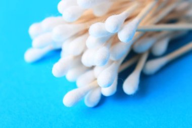 Beyaz pamuk uçlu temizleme bezi, bud. Kulak yakın mavi bir arka plan üzerinde sopa