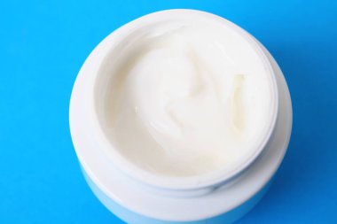 Mavi arka plan üzerinde vücut kremi ile jar