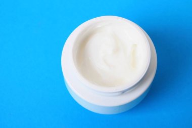 Mavi arka plan üzerinde vücut kremi ile jar