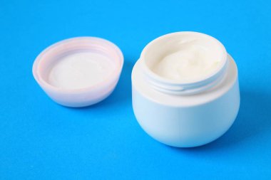 Mavi arka plan üzerinde vücut kremi ile jar