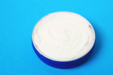 Mavi arka plan üzerinde vücut kremi ile jar