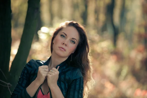 Fille en feuilles d'automne dans une veste en cuir — Photo