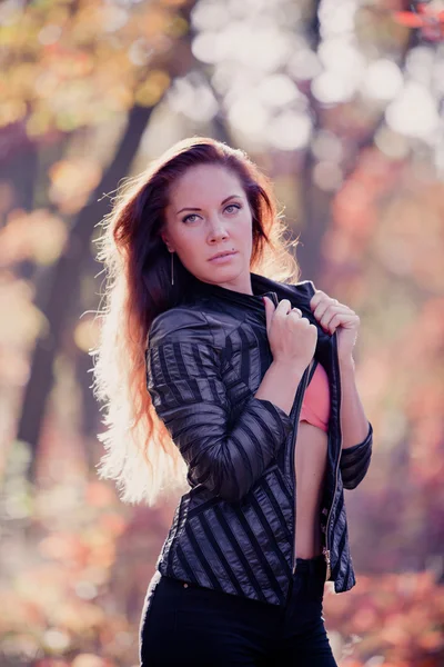 Fille en feuilles d'automne dans une veste en cuir — Photo