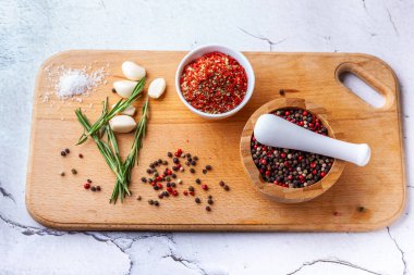 Ahşap bir tahtada baharat doğrama seti: biberiye, sarımsak, biber, paprika