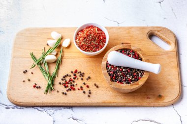 Ahşap bir tahtada baharat doğrama seti: biberiye, sarımsak, biber, paprika