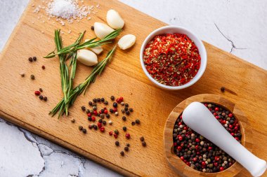 Ahşap bir tahtada baharat doğrama seti: biberiye, sarımsak, biber, paprika