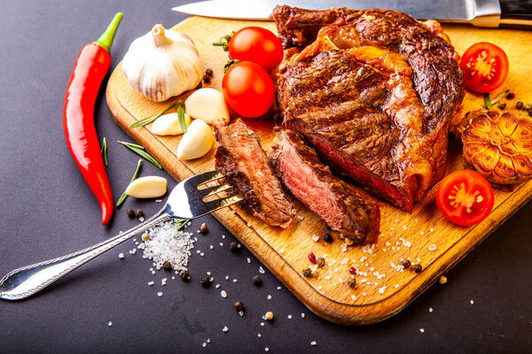 Fresh juicy ribeye steak with a set of spices on a cutting board