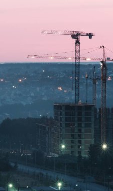 Kule vinçleri, gün batımında ya da gün doğumunda kentteki bir inşaat alanında yeni bir apartman inşaatı. Kârlı yatırımlar ve yenileme programı, geliştirme, inşaat endüstrisi konsepti
