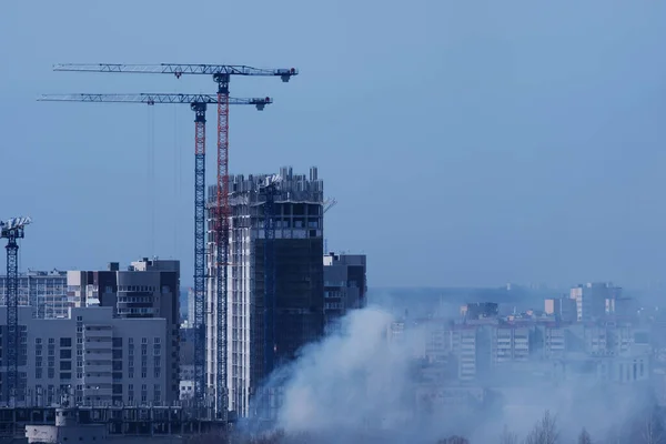 Tower cranes, the construction of a new tall apartment building at a construction site. Profitable investments and renovation program, development, construction industry concept in Russia