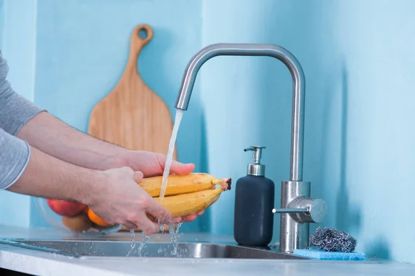 Homem Lava Bananas Numa Pia Numa Cozinha Com Paredes Azuis — Fotografia de Stock