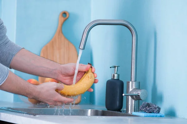 Homem Lava Bananas Numa Pia Numa Cozinha Com Paredes Azuis — Fotografia de Stock