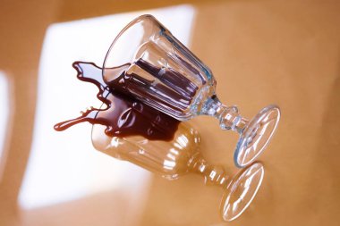 Cam bir kadeh, üzerine şarap ya da kahve dökülmüş sarı cam bir masanın üzerinde yatar. Sağlık hizmetleri ya da günlük temizlik.