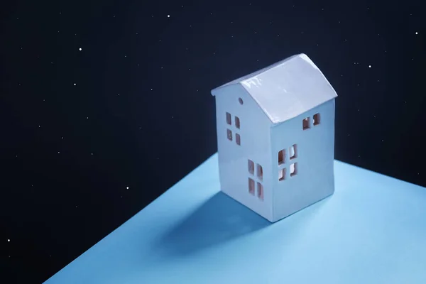明るい色とカラフルな小さな星と暗い空間の背景に青い表面にかわいい居心地の良い家のショット 上からの眺め 45角度表示 コンセプト 自宅に滞在 左側のテキストの空のスペース — ストック写真