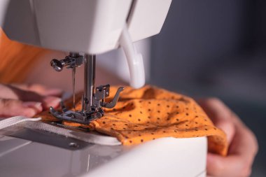 Birisi turuncu bir maske dikiyor.