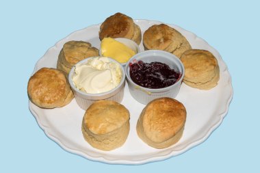 Çörekler tereyağı, reçel ve krema ile mavi bir arka plan üzerinde izole büyük bir plaka üzerinde