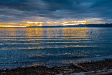 Işık ışınları Puget Sound 'un üzerindeki kara bulutların arasından süzülüyor..