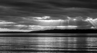Güneşin ışınları Washington 'daki Puget Sound üzerinde kara bulutları aşıyor..
