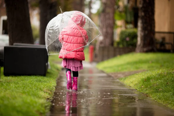 Une jeune fille joue sous la pluie californienne si nécessaire . Photo De Stock