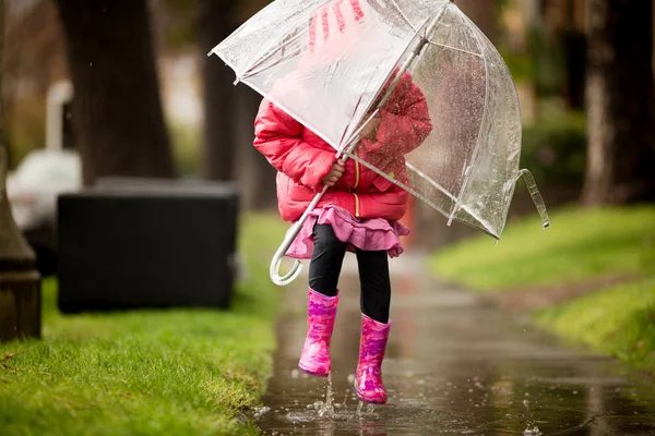 Une jeune fille joue sous la pluie californienne si nécessaire . Images De Stock Libres De Droits