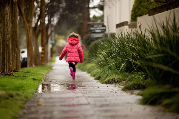 Une jeune fille joue sous la pluie californienne si nécessaire . Photos De Stock Libres De Droits