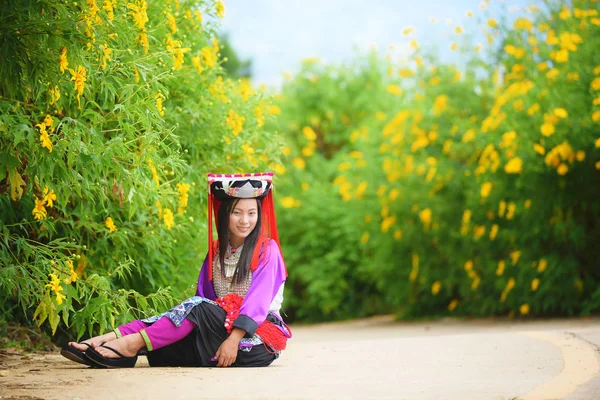 Belle asiatique jeune dame Lahu tribu en robe personnalisée assis au champ de tournesol mexicain avec sourire et heureux . — Photo