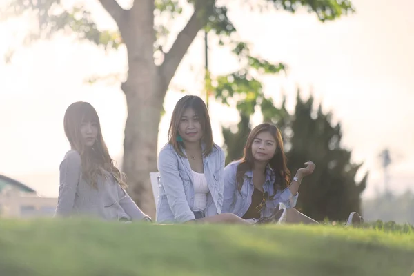 Tres asiático las mujeres sentarse en hierba en sunnyday . — Foto de Stock