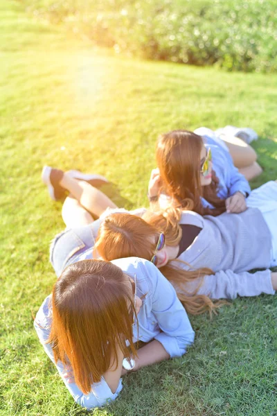 Hermosas chicas asiáticas tumbadas en la hierba verde bajo la luz del sol — Foto de Stock