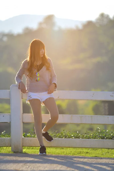 Mujer joven está de pie junto a una valla en un rancho en tonos cálidos — Foto de Stock