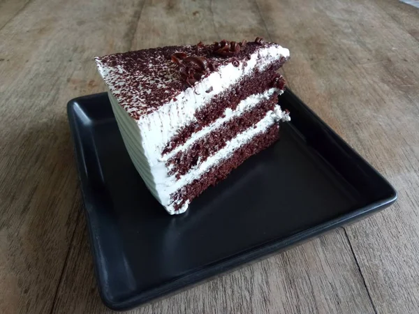 Kafede ahşap masa üzerinde siyah plaka içinde çikolatalı kek parçası.